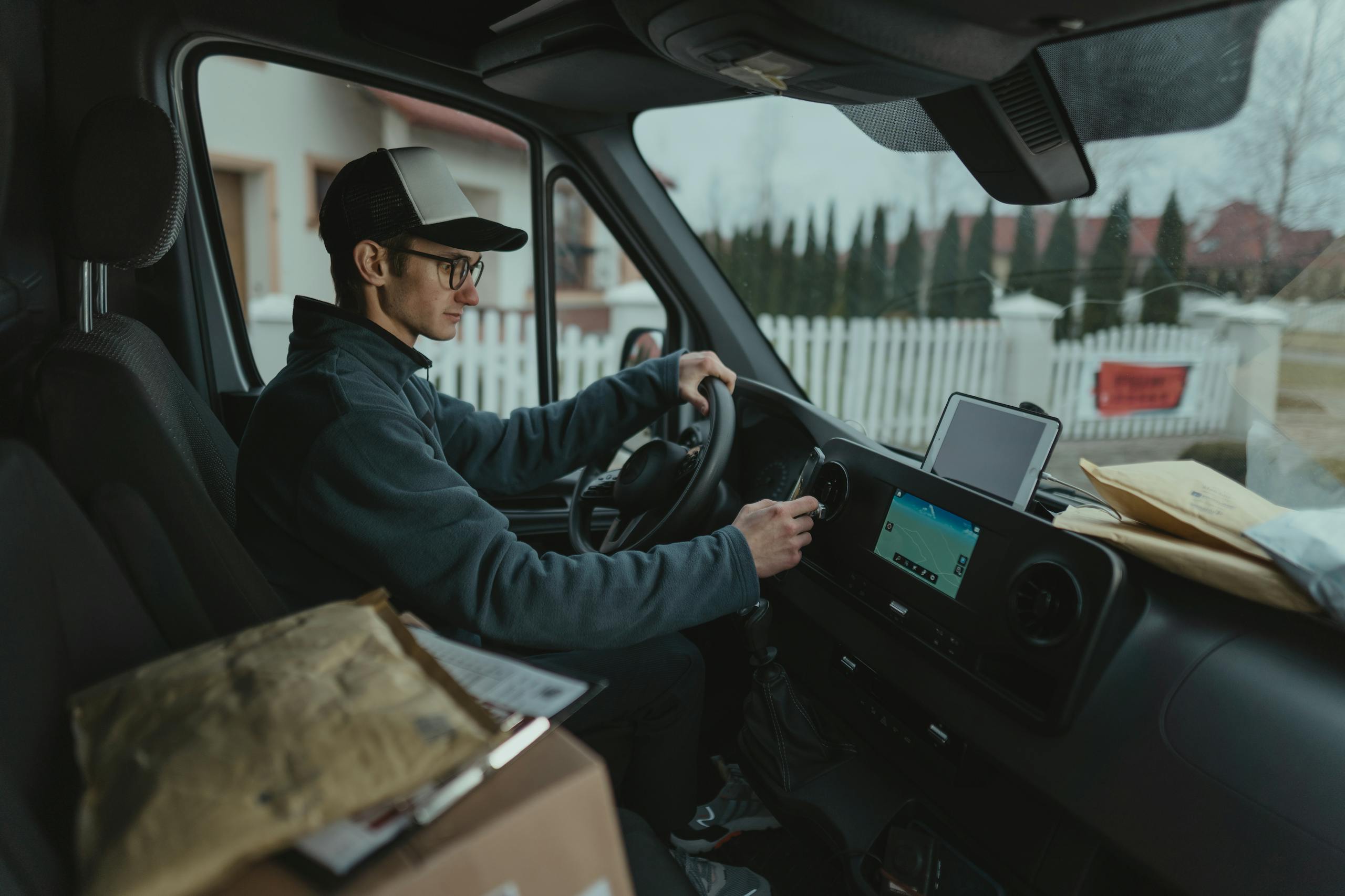 Courier driving van with packages, using GPS for efficient delivery route.